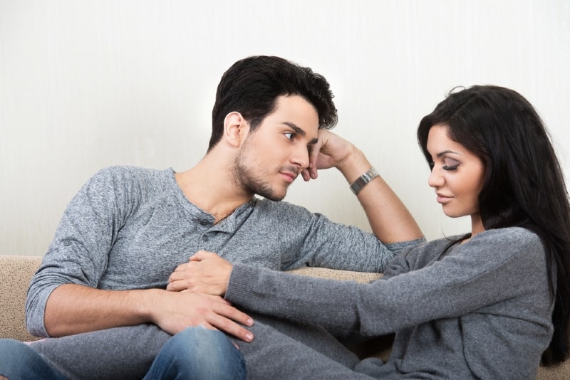 man looking at woman while sitting on sofa