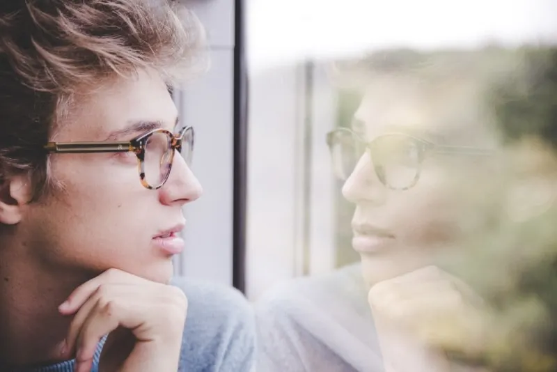 man with eyeglasses looking through window