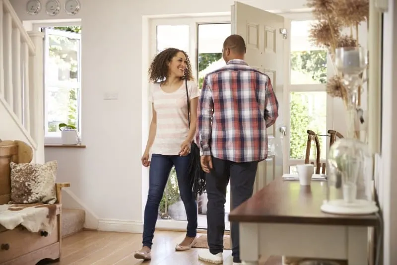 man opening front door for smiling woman