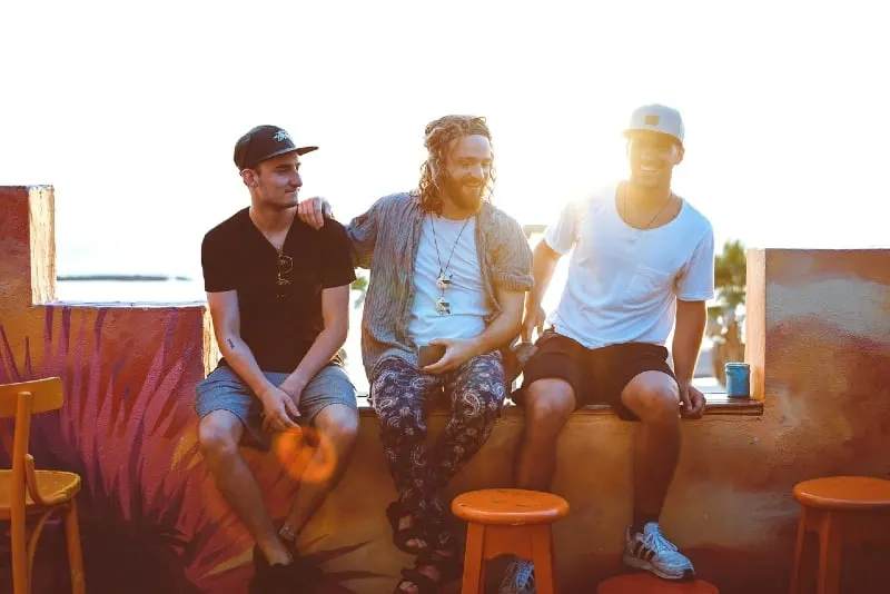 three men sitting on veranda and talking