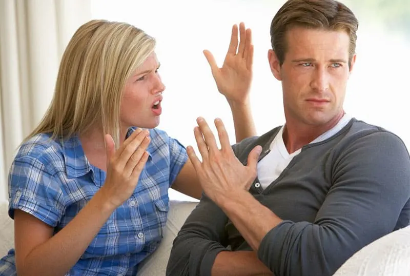 man stopping the woman from nagging/ talking sitting in the sofa