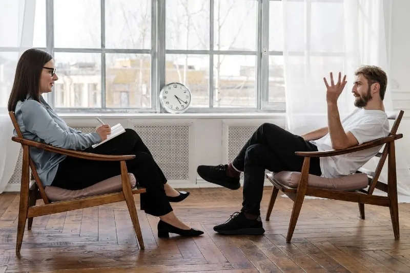 man talking to woman while sitting on chair