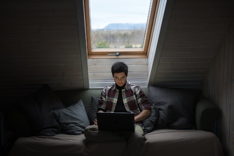 man typing on laptop while sitting on sofa