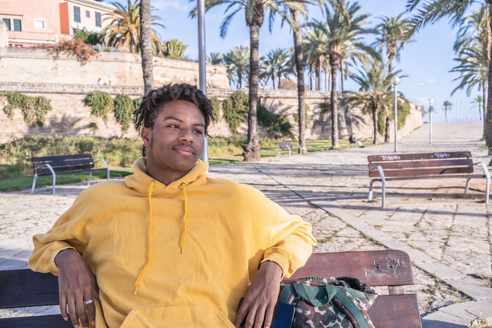 man with yellow sweatshirt sitting on the bench