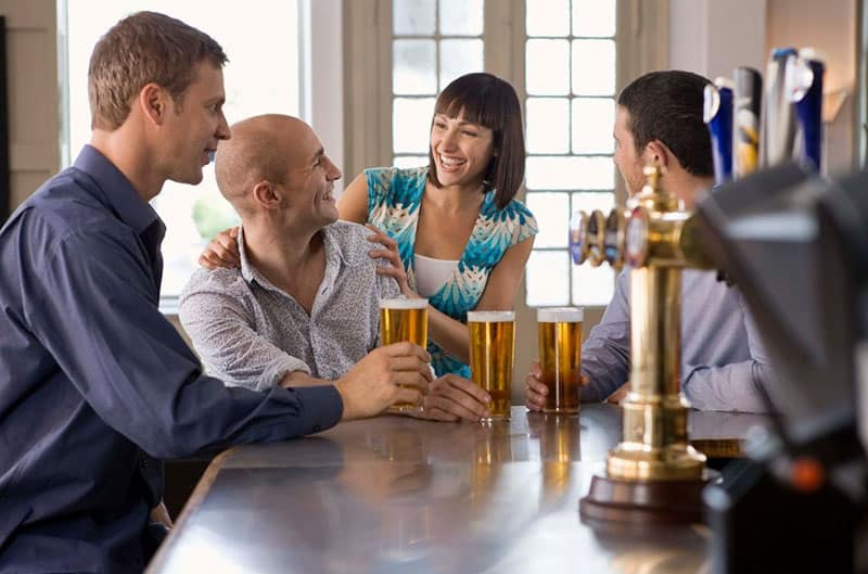 men and woman flirting in a bar while drinking beer