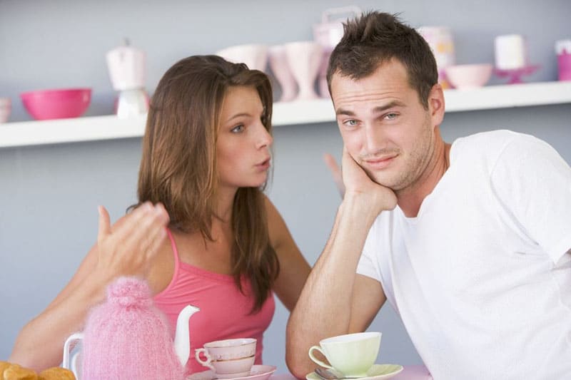 nagging young woman to a man sitting next to her while having their tea time inside the dining area