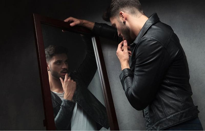 narcissists young man facing the mirror wearing black jacket