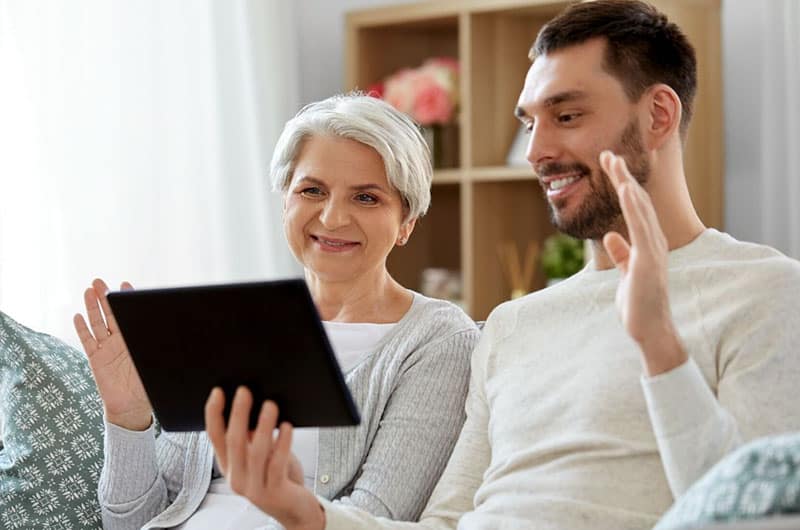 old woman and son facing and waving onto the tablet