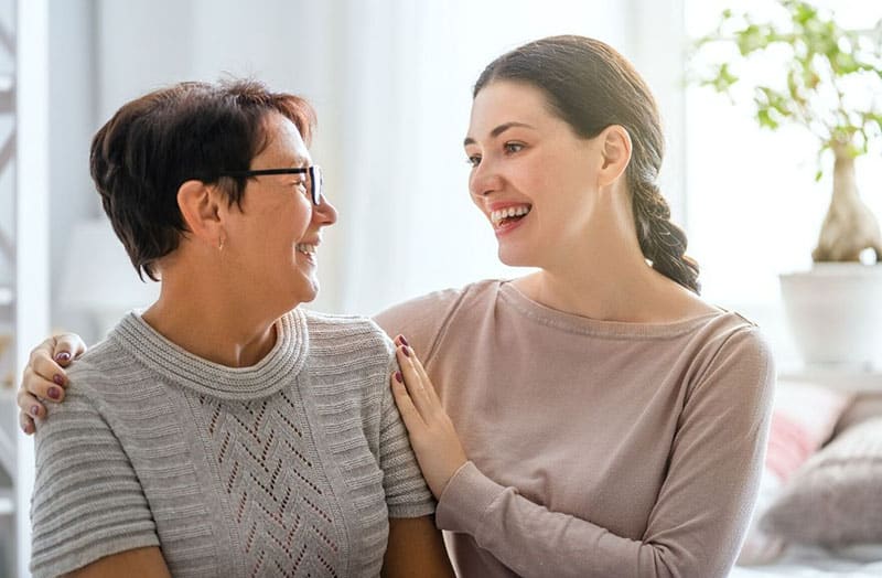 uma mulher idosa senta-se ao lado de uma mulher mais nova na sala de estar