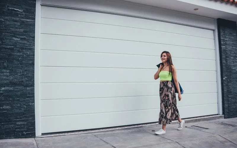 pretty woman walking in sidewalk near a closed garage