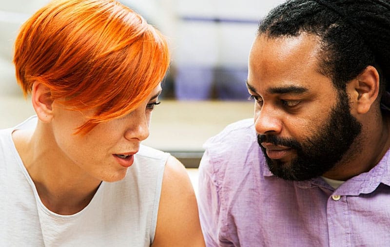 red haired woman talking to a black man with serious faces