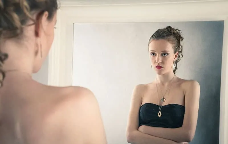 sad rich woman looking at herself in the mirror