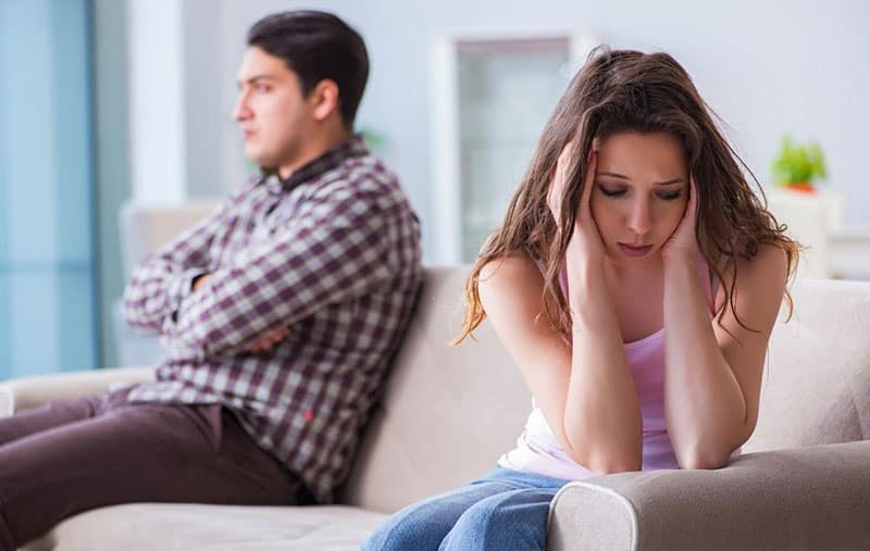 sorrowful woman sitting next to a man in a sofa inside living room
