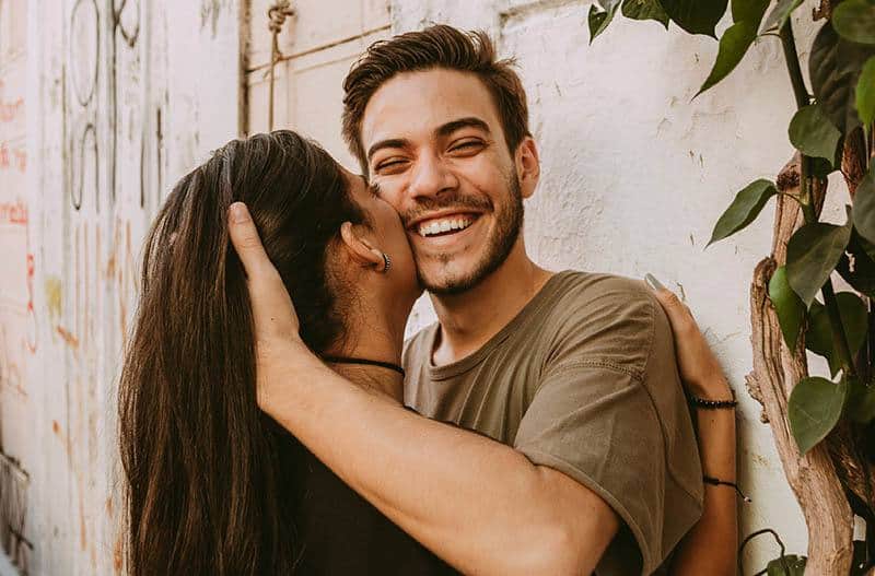 the brunette kisses the cheek of the smiling man