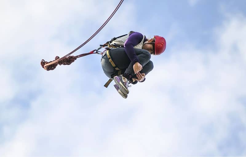 donna che fa bungee jumping in aria rimboccandosi i piedi 