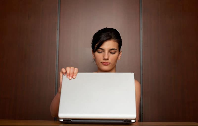woman closing laptop placed on a table 