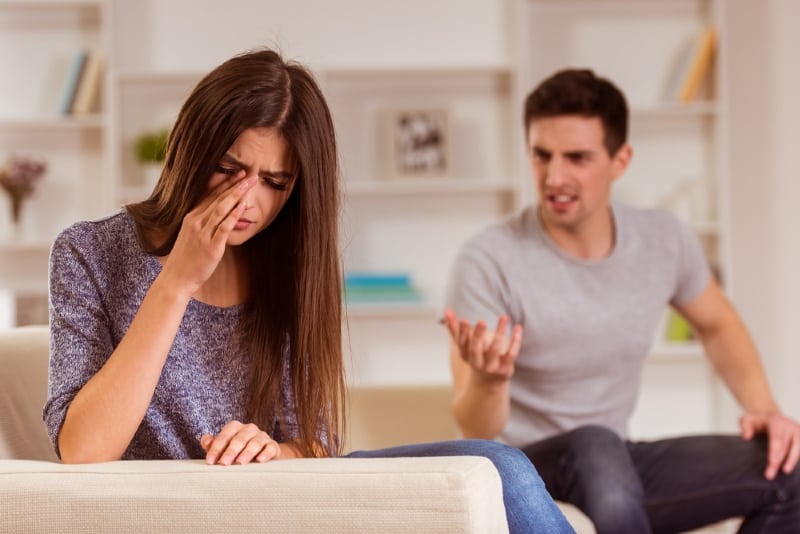 woman crying while sitting near angry man