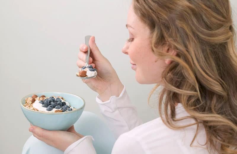 woman eating smoothie holding a spoon in a sideview