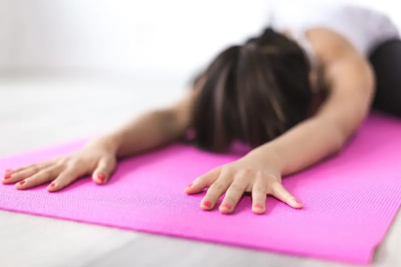 woman exercising yoga on pink mat