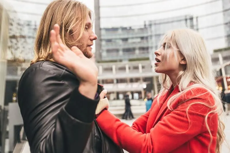 woman grasping man's coat outdoors in broad daylight