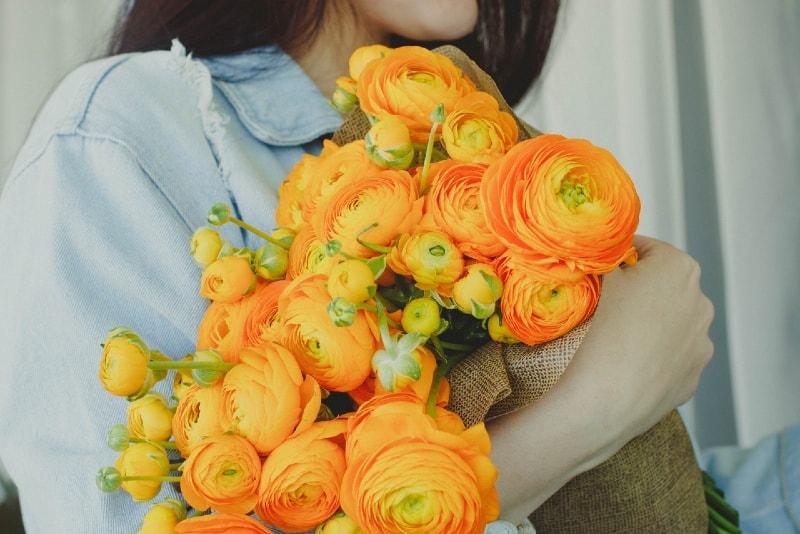 donna con fiori gialli e arancioni in mano