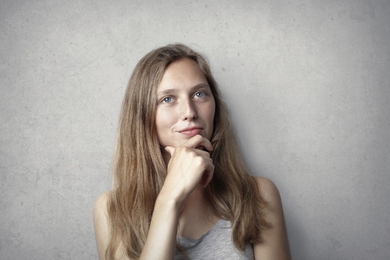 woman in gray top holding her chin