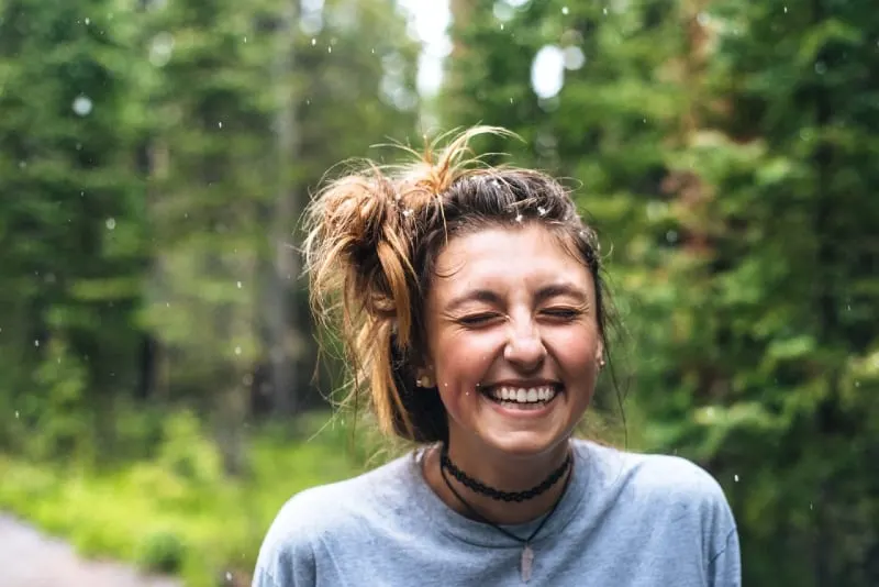woman laughing while standing near tree