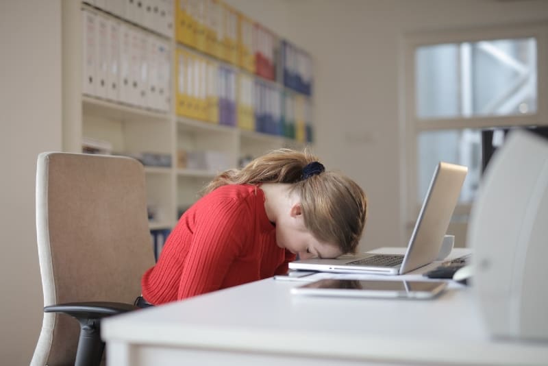 donna in top rosso appoggiata al laptop mentre è seduta su una sedia