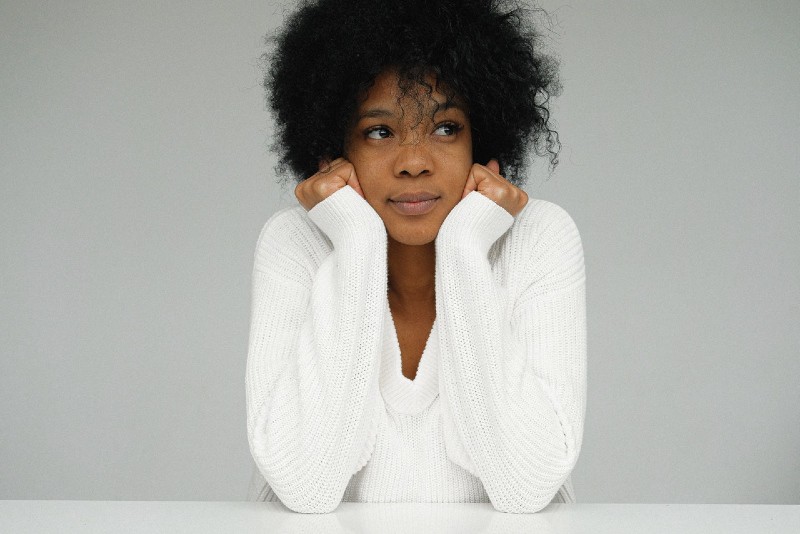 woman in white sweater leaning on table