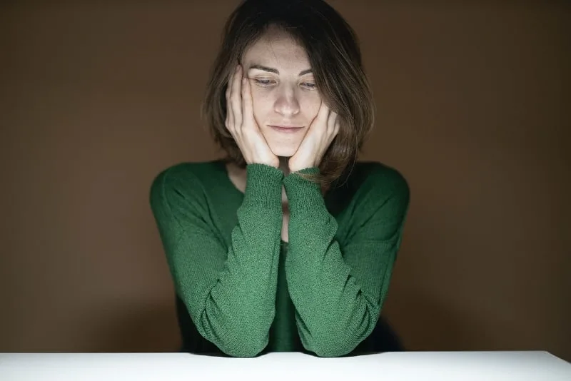 woman in green shirt leaning on table