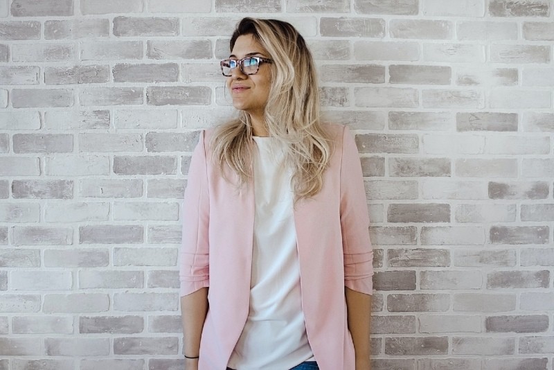 mulher de blazer cor-de-rosa encostada à parede