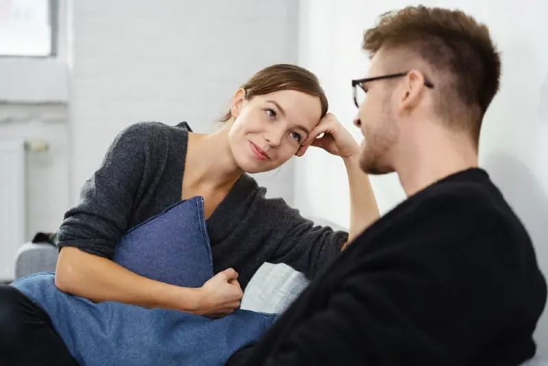 woman looking at man while sitting on sofa