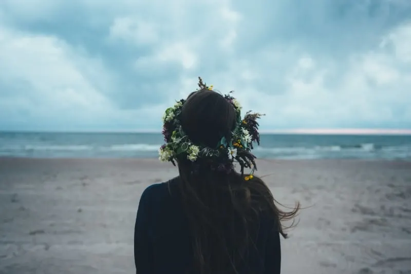woman with flower crown looking at sea