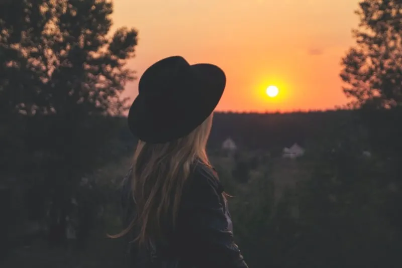 woman in black hat looking at sunset