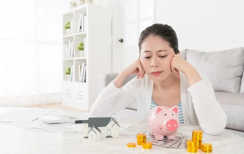 woman planning alone looking at the piggybank money and a small house in the table