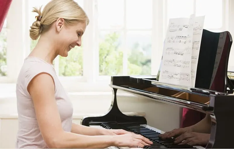 woman play piano smiling wearing white dress