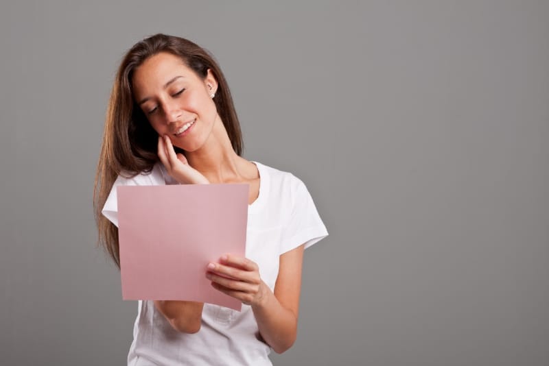 smiling woman in white t-shirt reading letter