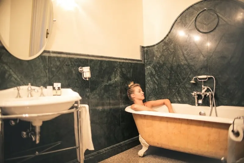 woman with eyes closed relaxing in bathtub