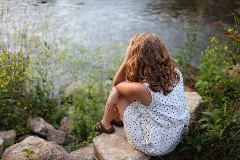 woman sitting by the lake wearing polka dot dress
