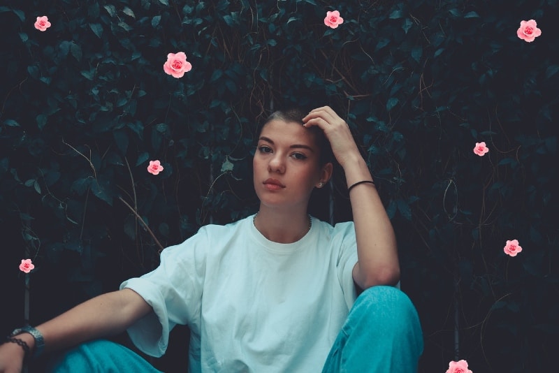 woman in white t-shirt sitting near pink flowers