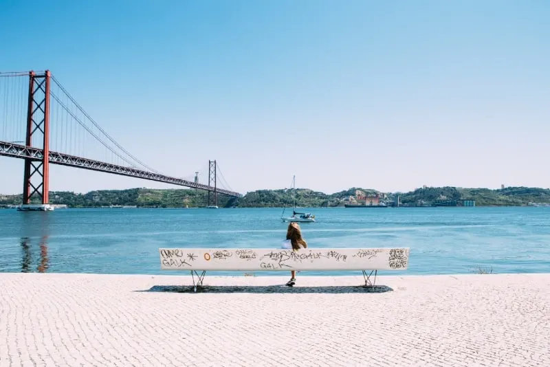 woman sitting on bench looking at water
