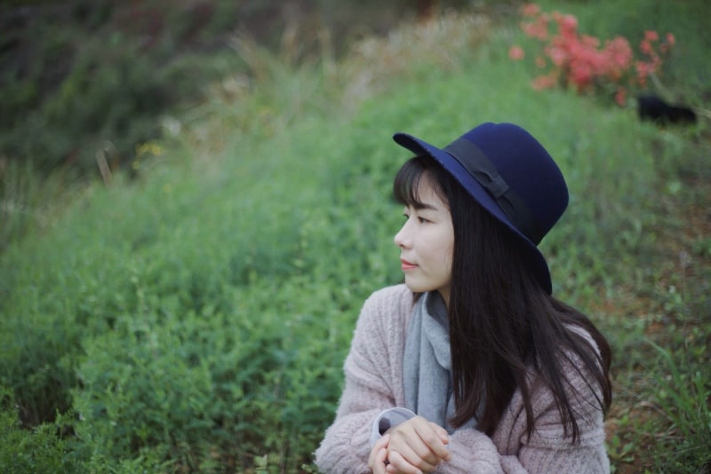 donna con cappello blu seduta sull'erba
