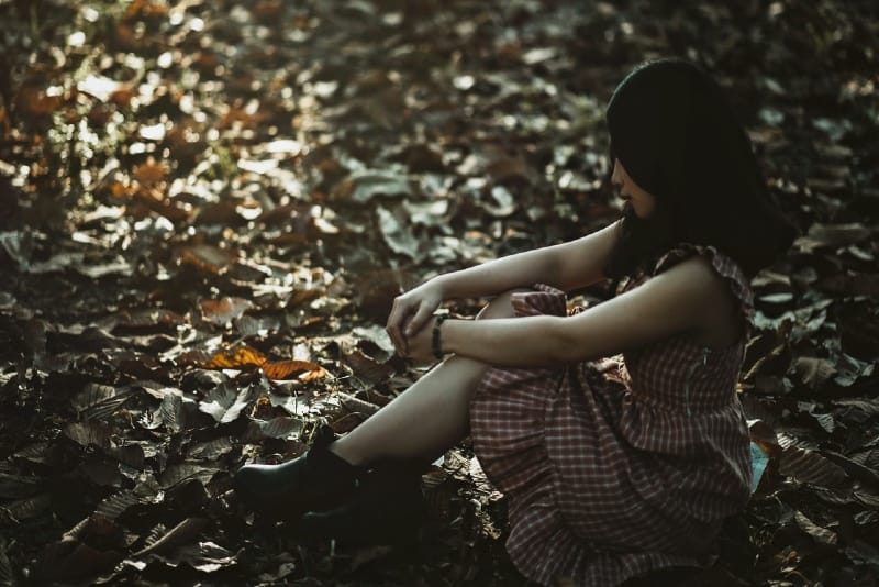 woman in checked dress sitting on leaves