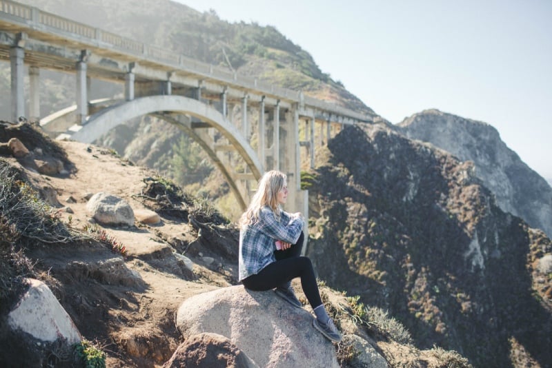 blonde woman in plaid shirt sitting on rock