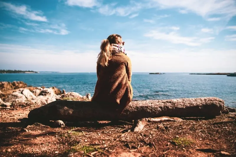 woman sitting on rock looking at water