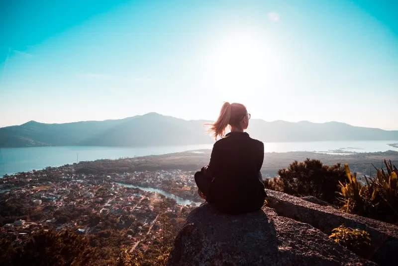 woman sitting on rock looking at mountain