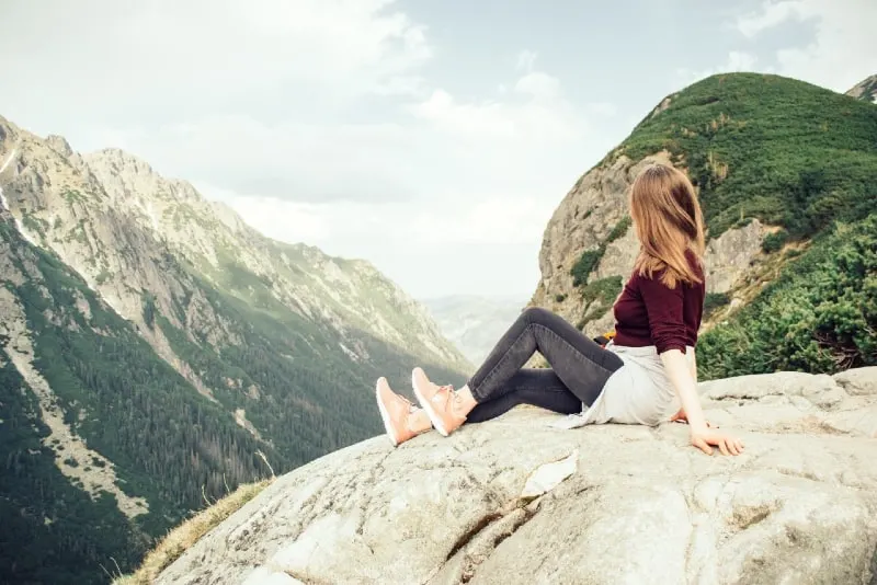 woman sitting on rock looking at mountain