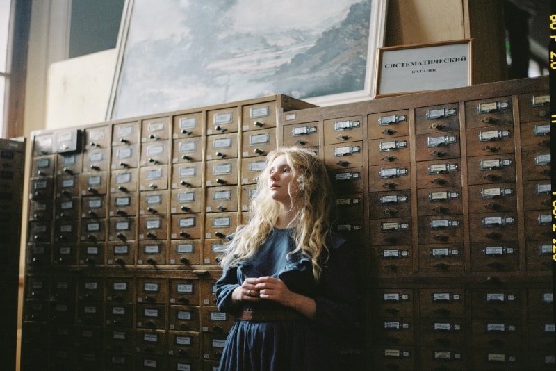 woman in blue dress standing beside brown cabinet