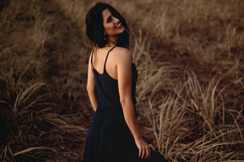 mujer sonriente vestida de pie en el campo