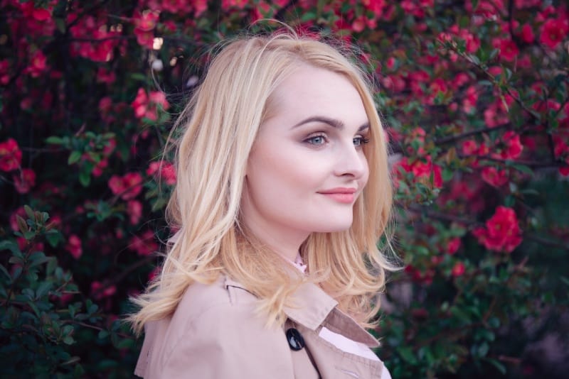 blonde woman standing near red flowers